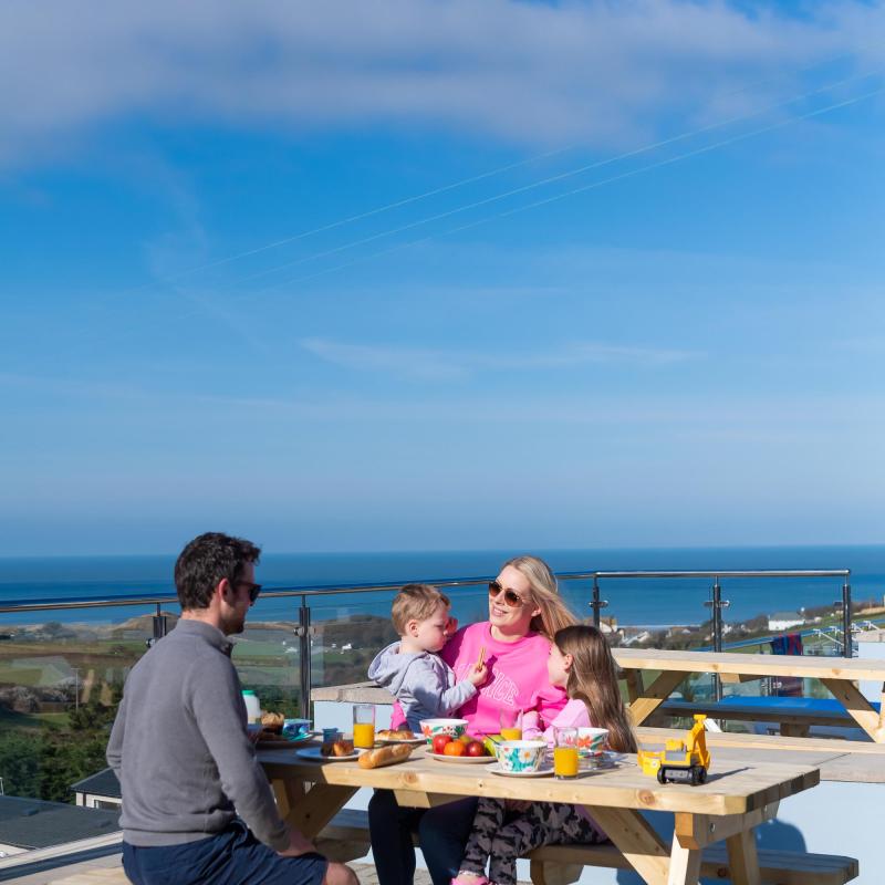 Woolacombe Sands Holiday Park Guests on Bench outside their Chalet with View of the Sea