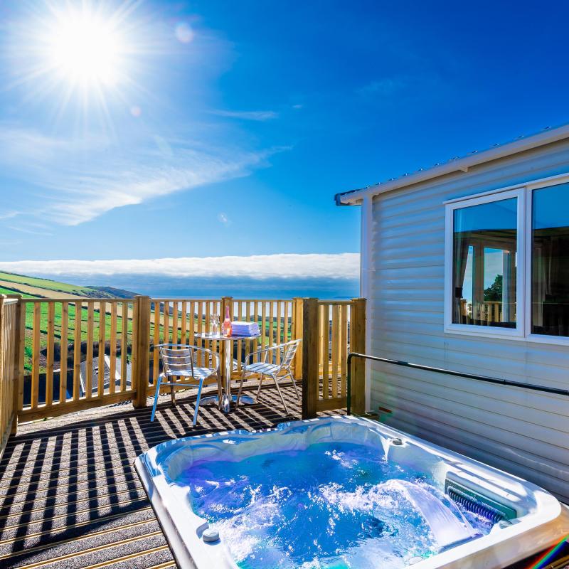 A hot tub on the decking overlooking the countryside and sea outside one of the caravans at Woolacombe Sands Holiday Park