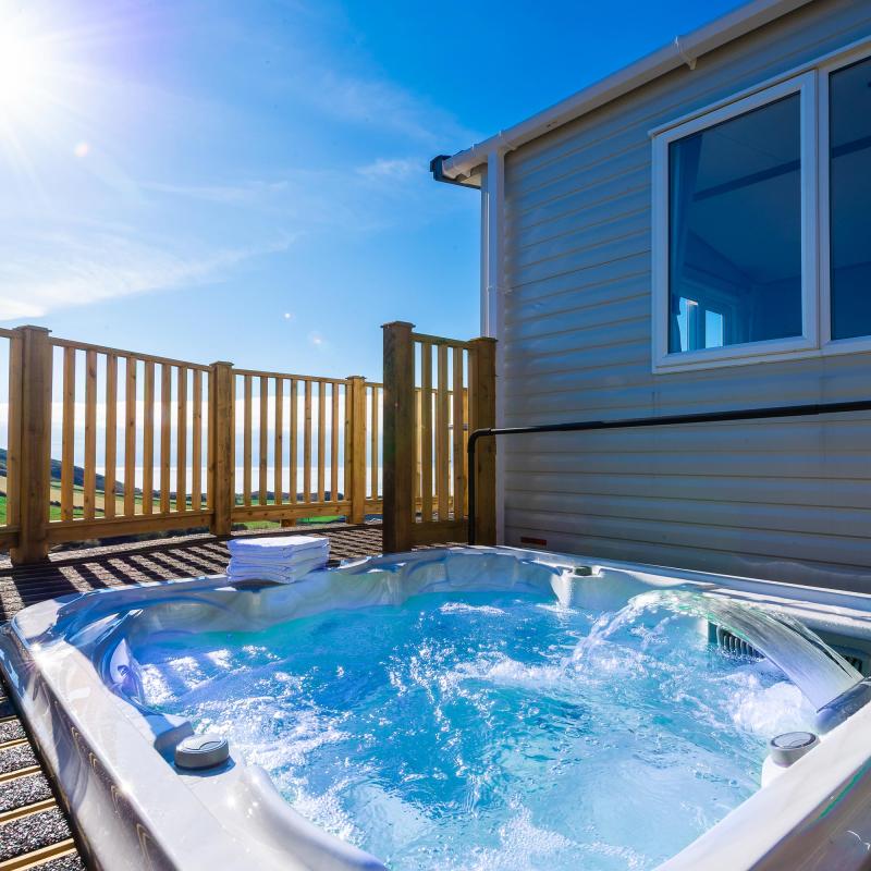 A hot tub on the decking overlooking the countryside and sea outside one of the caravans at Woolacombe Sands Holiday Park
