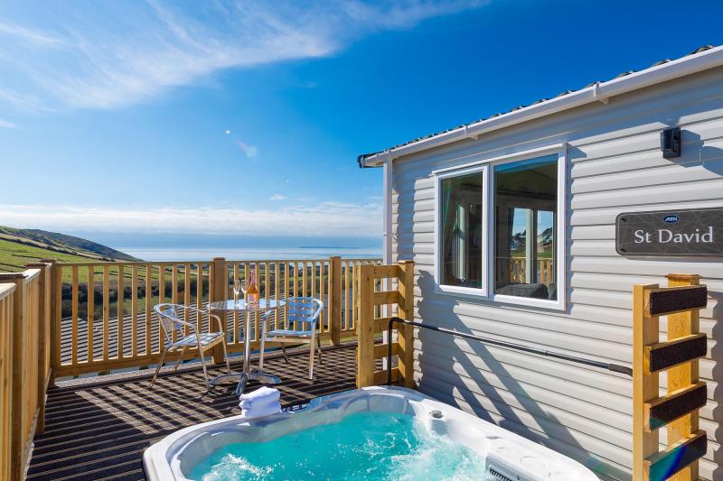 A hot tub on the decking of a caravan at Woolacombe Sands Holiday Park with views of the sea and countryside
