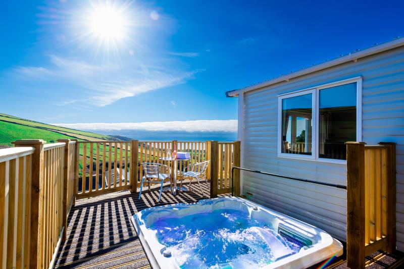 A hot tub on the decking overlooking the countryside and sea outside one of the caravans at Woolacombe Sands Holiday Park