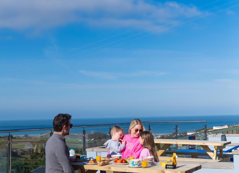 Woolacombe Sands Holiday Park Guests on Bench outside their Chalet with View of the Sea