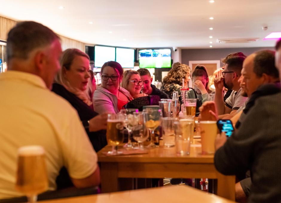Guests sat at tables with their drinks in the Woolacombe Sands Holiday Park Clubhouse bar area