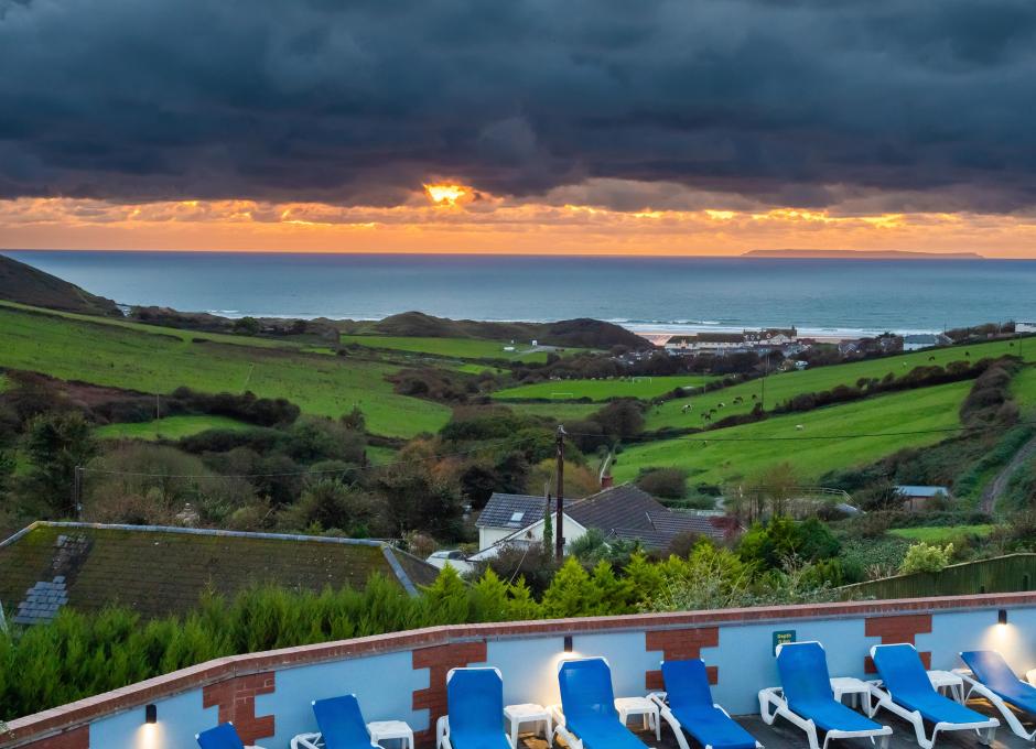 A view of the sunset over the sea from Woolacombe Sands Holiday Park's outdoor swimming pool