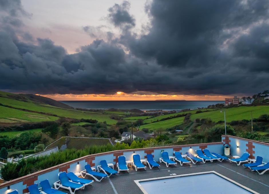Woolacombe Sands Holiday Park's outdoor swimming pool at sunset with a view over the sea in the distance